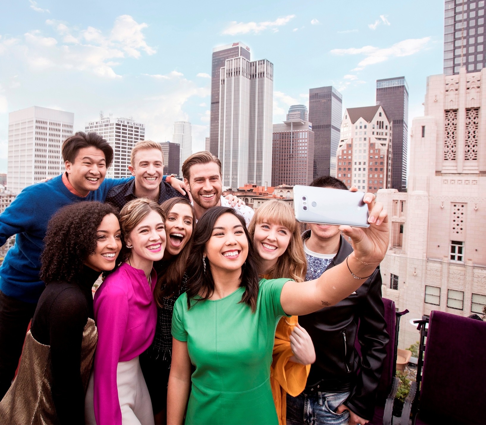 A group of people take a group selfie with the LG G6 in Ice Platinum in front of the New York skyline