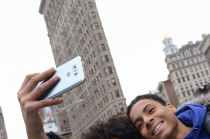 A man and woman take a selfie with the LG G6 in Ice Platinum in front of the Flatiron Building in New York, USA
