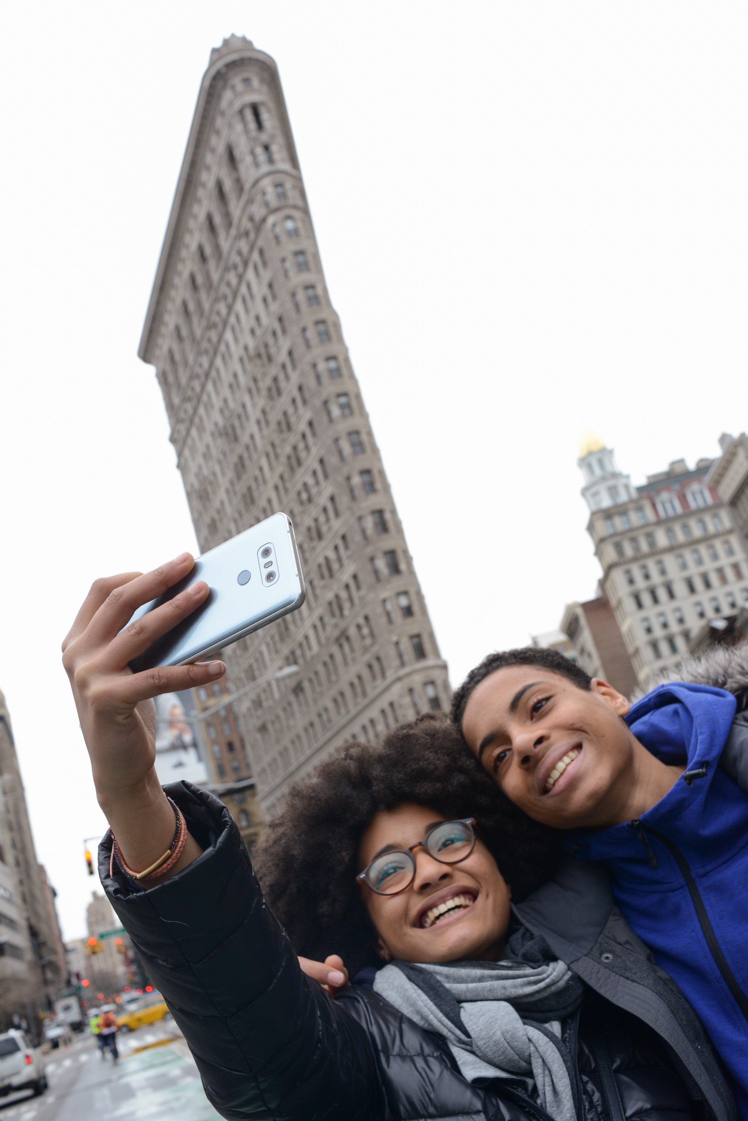 A man and woman take a selfie with the LG G6 in Ice Platinum in front of the Flatiron Building in New York, USA