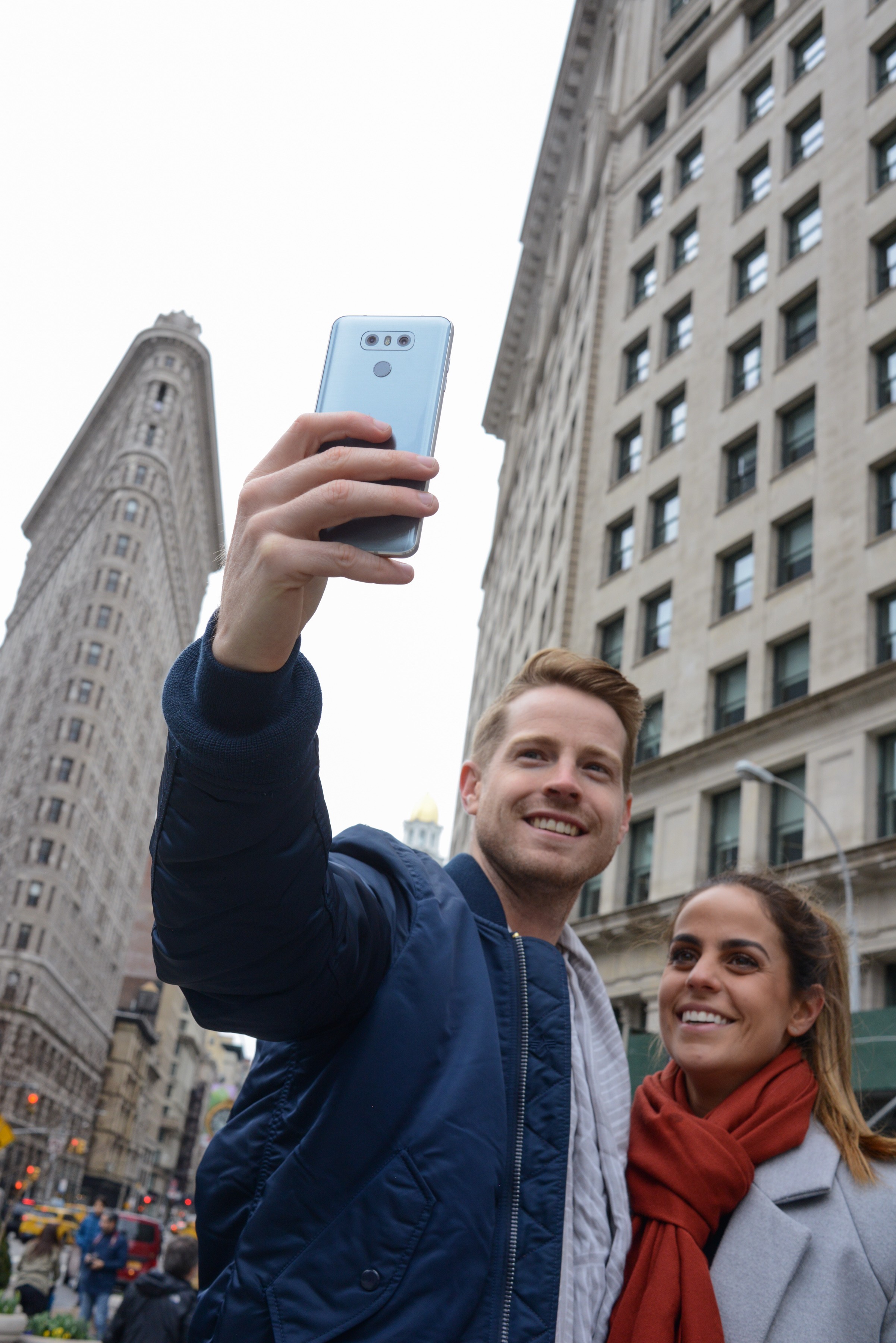 A man and woman take a selfie with the LG G6 in Ice Platinum in front of the Flatiron Building in New York, USA