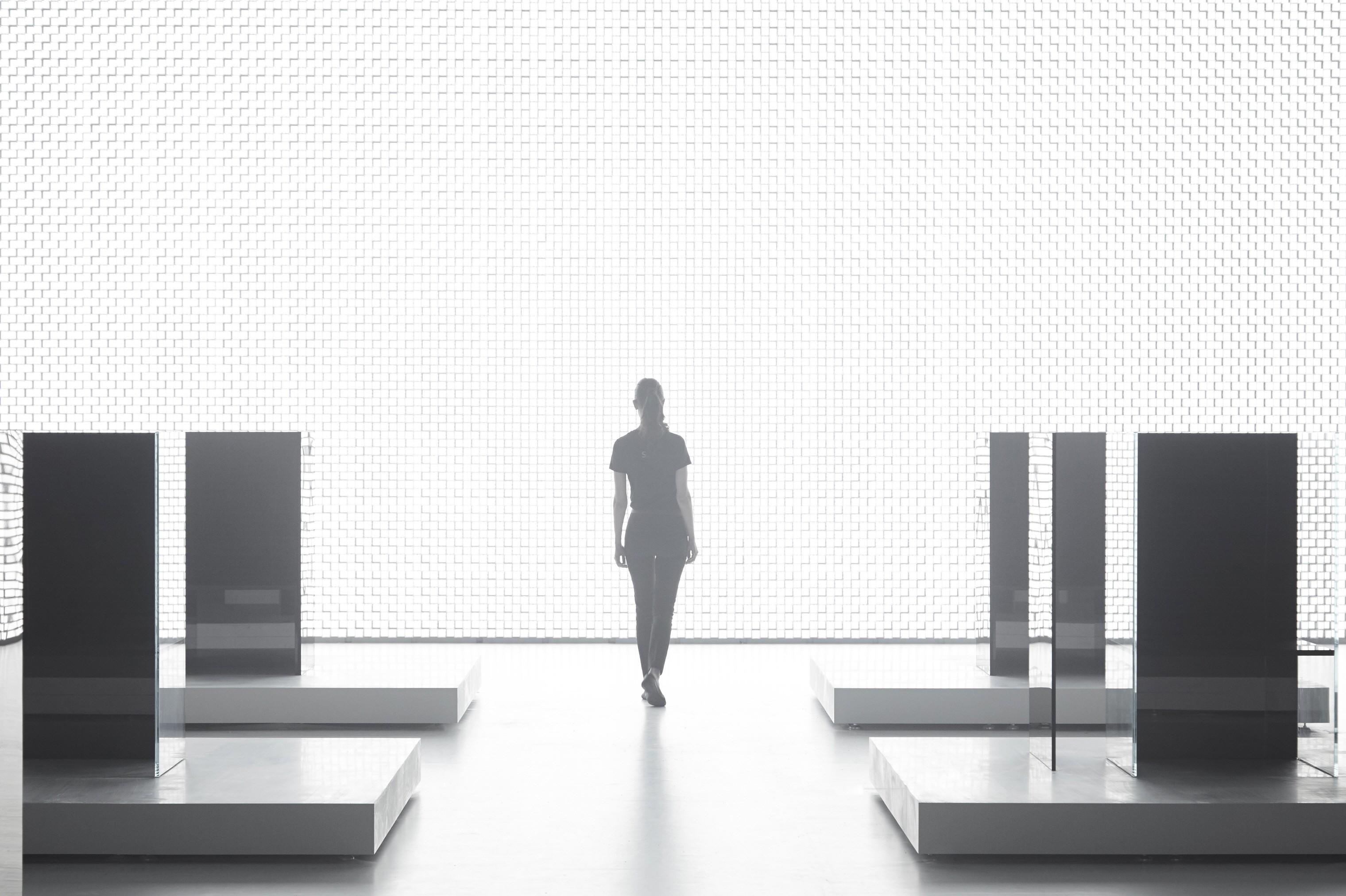 A woman is seen in the background walking beside the back wall of Tokujin Yoshioka’s art exhibition, which boasts thousands of bright lights.
