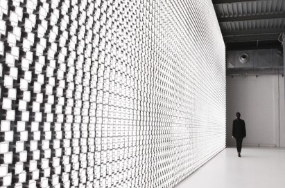 A woman is seen in the background walking beside the back wall of Tokujin Yoshioka’s art exhibition, which boasts thousands of bright lights.