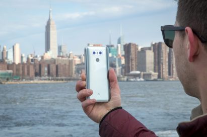 A man holds the LG G6 in Ice Platinum against the New York skyline, showing off the back side of the device