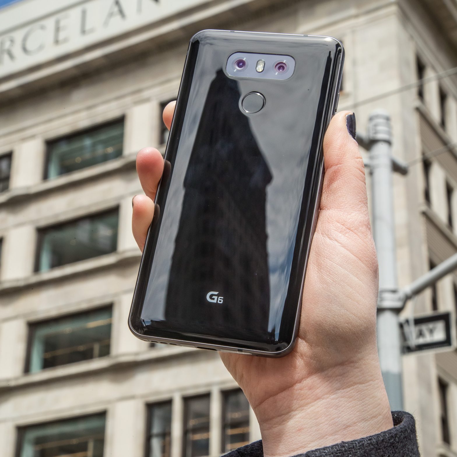 A person holds the LG G6 in Astro Black up in front of a New York building, showing off the back side of the device
