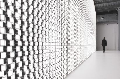 A woman is seen in the background walking beside the back wall of Tokujin Yoshioka’s art exhibition, which boasts thousands of bright lights.