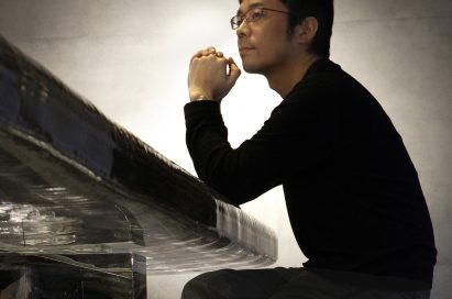 Side profile of Tokujin Yoshioka seated on a table