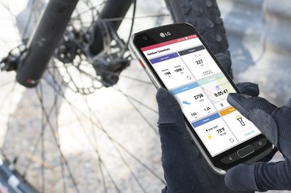 A person in front a bike holding the LG X venture, looking at exercise records on the device’s Outdoor Essentials app
