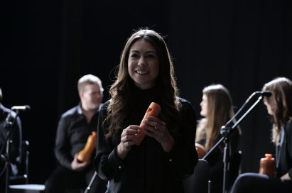 A lady from the London Vegetable Orchestra posing with an instrument she made using just a carrot.