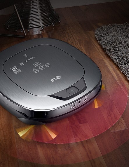LG HOM-BOT Turbo+ navigating across a hard wood floor and obstacles such as a living room carpet, a decorative piece and a chair leg.
