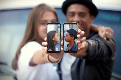 A young couple each hold the LG Q6 in their holds, each displaying a picture of themselves giving air kisses
