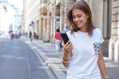 A woman walking down the street while looking at the LG G6 in her hand