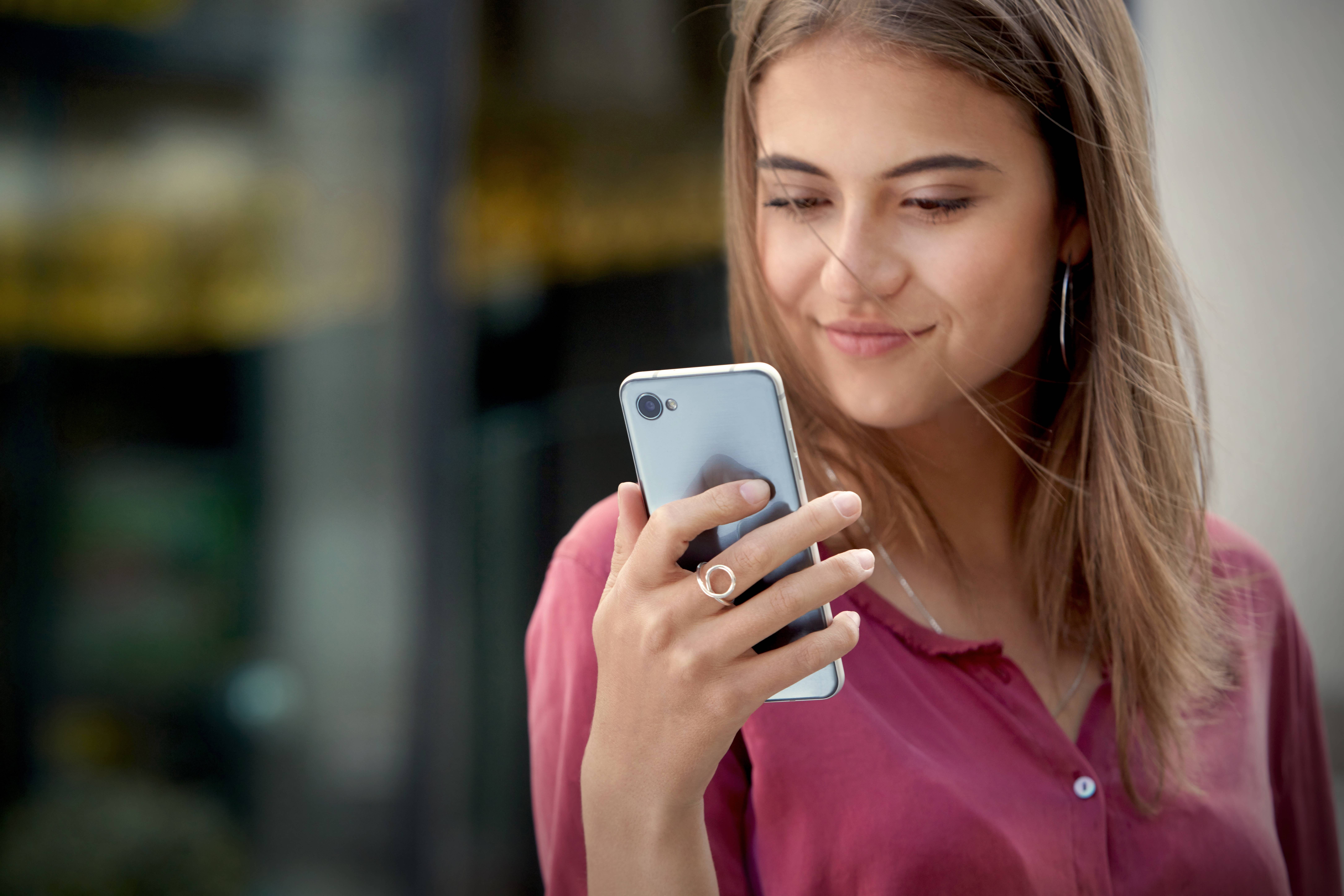 A woman looking at the LG G6 in her hand