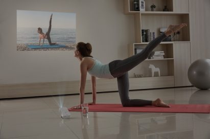 A woman follows a yoga instruction video with the help of the LG MiniBeam Projector