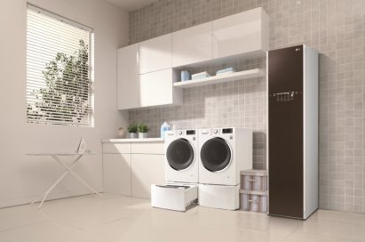 LG Styler and one LG washing machine with the TWINWash™ Mini unit open next to LG dryer with the pedestal unit closed in a laundry room with tiled walls