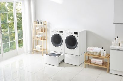 Side view of one LG washing machine with the TWINWash™ Mini unit open next to LG dryer with the pedestal unit closed in a laundry room