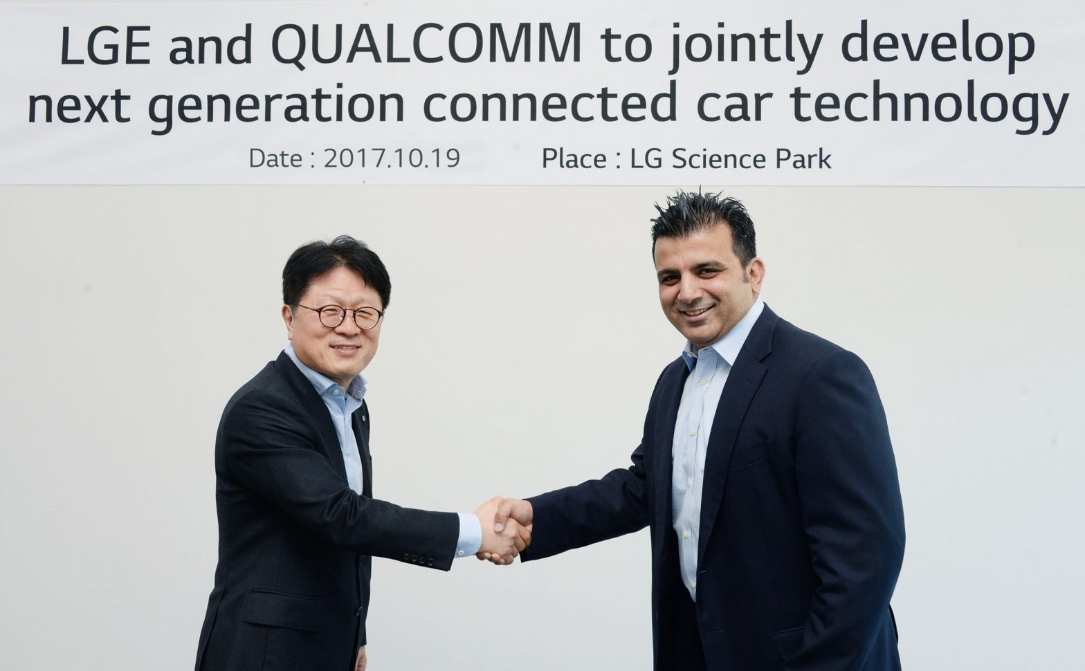 Kim Jin-yong, executive vice president of LG’s Vehicle Components Smart Business Unit, shake hands with Nakul Duggal, vice president of product management at Qualcomm Technologies, Inc, to celebrate the new agreement