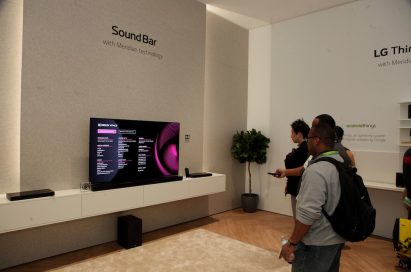 Visitors listen to audio on an LG sound bar connected to an LG TV in the CES LG Sound Bar highlight zone