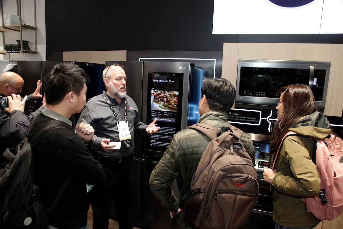 A gentleman explains the main features of the LG InstaView Door-in-Door Refrigerator to three visitors