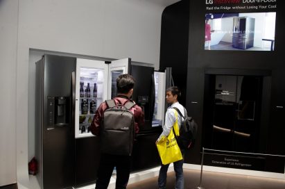 Two visitors open the LG InstaView Door-in-Door refrigerators on display at LG’s Home Appliance zone at CES 2018, while discussing its InstaView feature.