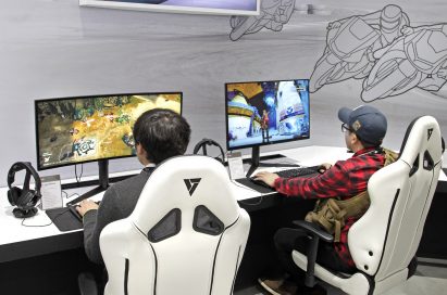 Two visitors sit on gaming chairs while playing games on LG’s 21:9 UltraWide Gaming monitors.