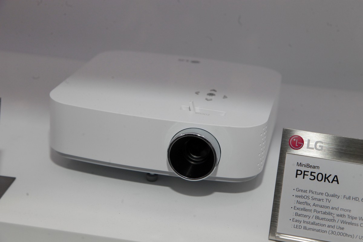 Upper front view of LG’s MiniBeam PF50KA projector placed next to its nameplate