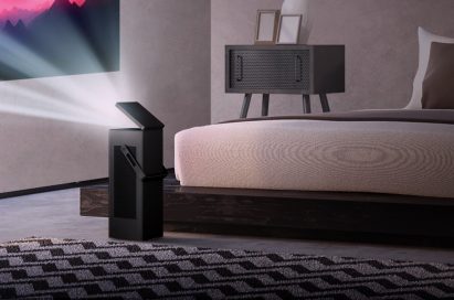 An LG 4K UHD projector set up in a bedroom projects video onto a wall from a short distance
