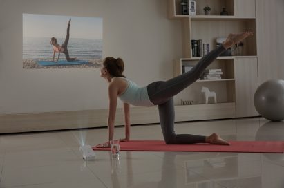 A woman doing yoga while watching a projection from the LG MiniBeam Projector