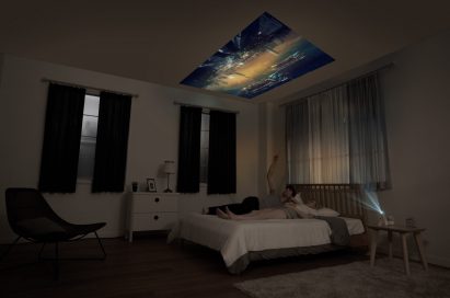 A couple lying in bed while watching a movie projected on the ceiling by the LG MiniBeam Projector