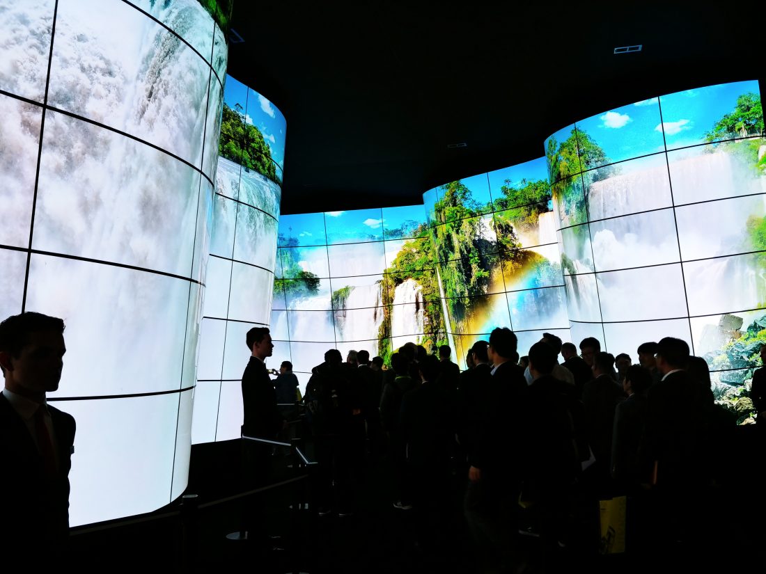 People standing before the entrance of the LG OLED Canyon, which displays a huge waterfall