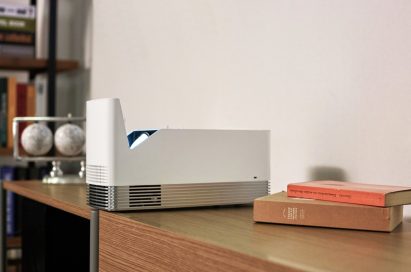 Side view of the LG ProBeam Projector HF85J put next to some books on a desk