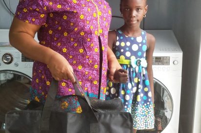 A woman stands with a little girl and smiles with LG’s gift bag in front of LG’s washing machine.