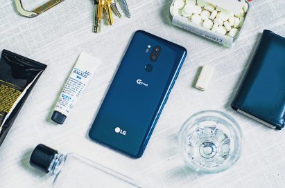 The LG G7 ThinQ in New Moroccan Blue face down on a table, next to other lifestyle items, such as keys, a water bottle, mints, etc.