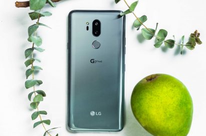 The LG G7 ThinQ in New Platinum Gray face down next to a green pear