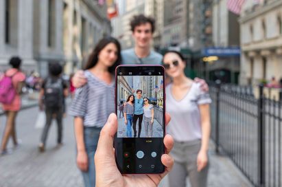 A person holding the LG G7 ThinQ and taking a picture of a group of people