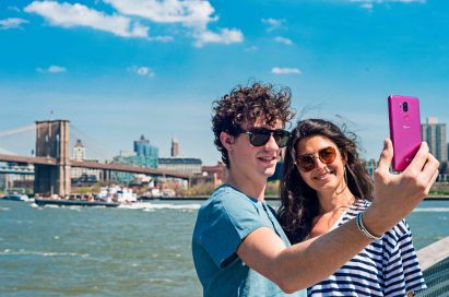 A man and woman taking a selfie in front of a riverfront with the LG G7 ThinQ in Raspberry Rose