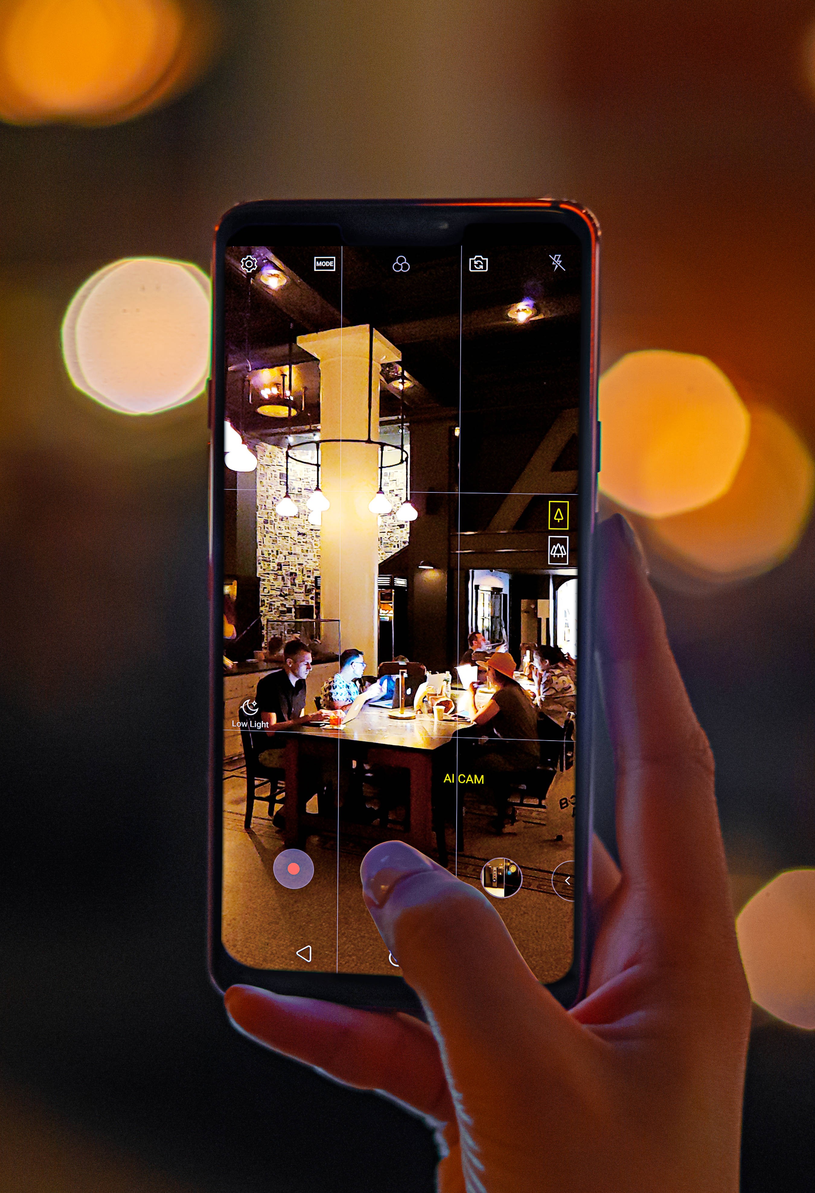 A person taking a photo of a dark cafe with AI CAM on the LG G7 ThinQ