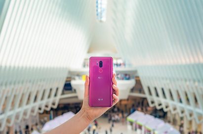A person holding the LG G7 ThinQ in Raspberry Rose with the rear view showing