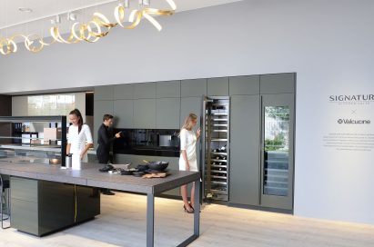 Woman trying cooktop, man trying wall oven and woman opening wine cellar at SIGNATURE KITCHEN SUITE’s exhibition hall cooperated with Valcucine at IFA 2018