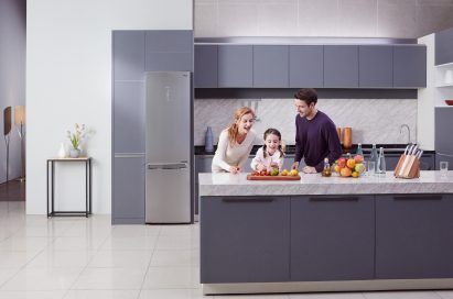Little girl and her parents cutting fruit on the counter with LG Centum System™ bottom-freezer refrigerator in the background