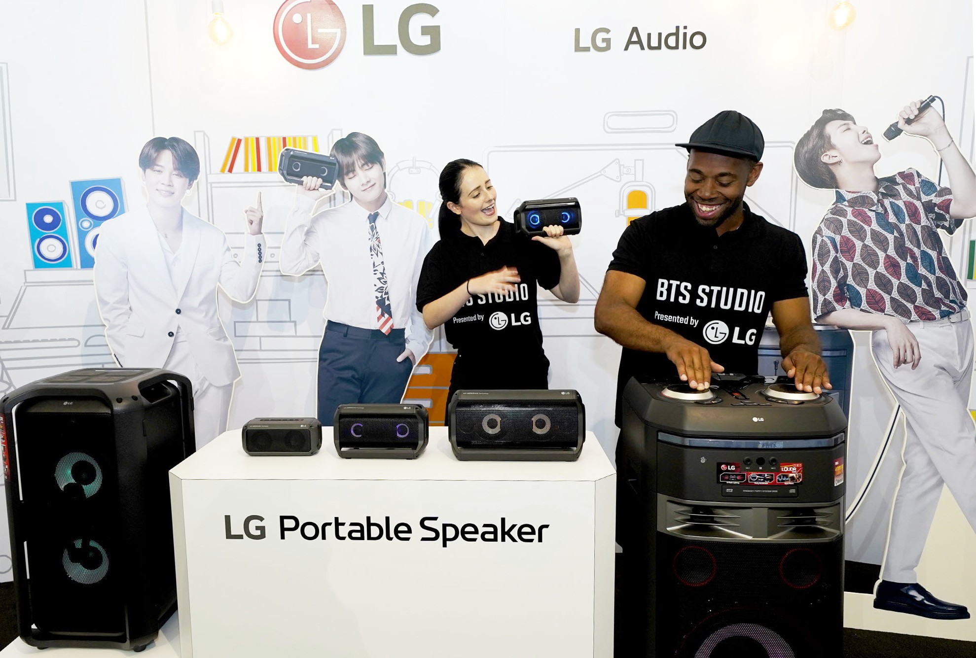 A man and woman both test LG’s speaker products at the BTS Studio Presented by LG.