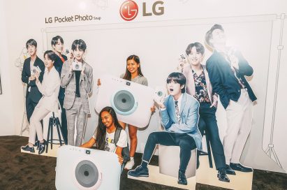 Visitors take a picture at the LG Pocket Photo Snap booth with cutouts of their favorite K-pop group.