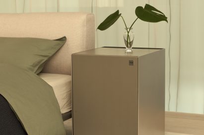 LG OBJET Air Purifier with a plant placed on top of it positioned next to a bed