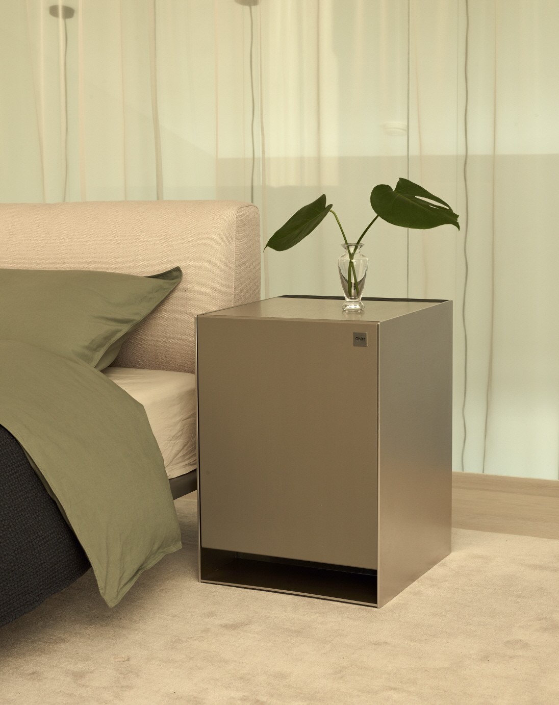 LG OBJET Air Purifier with a plant placed on top of it positioned next to a bed