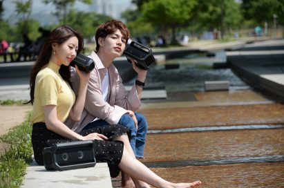 A man and a woman sitting outside enjoying music on their LG XBOOMs