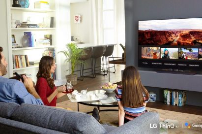 A family sits in the living room while looking at their travel photos via Google Assistant on LG’s ThinQ TV.