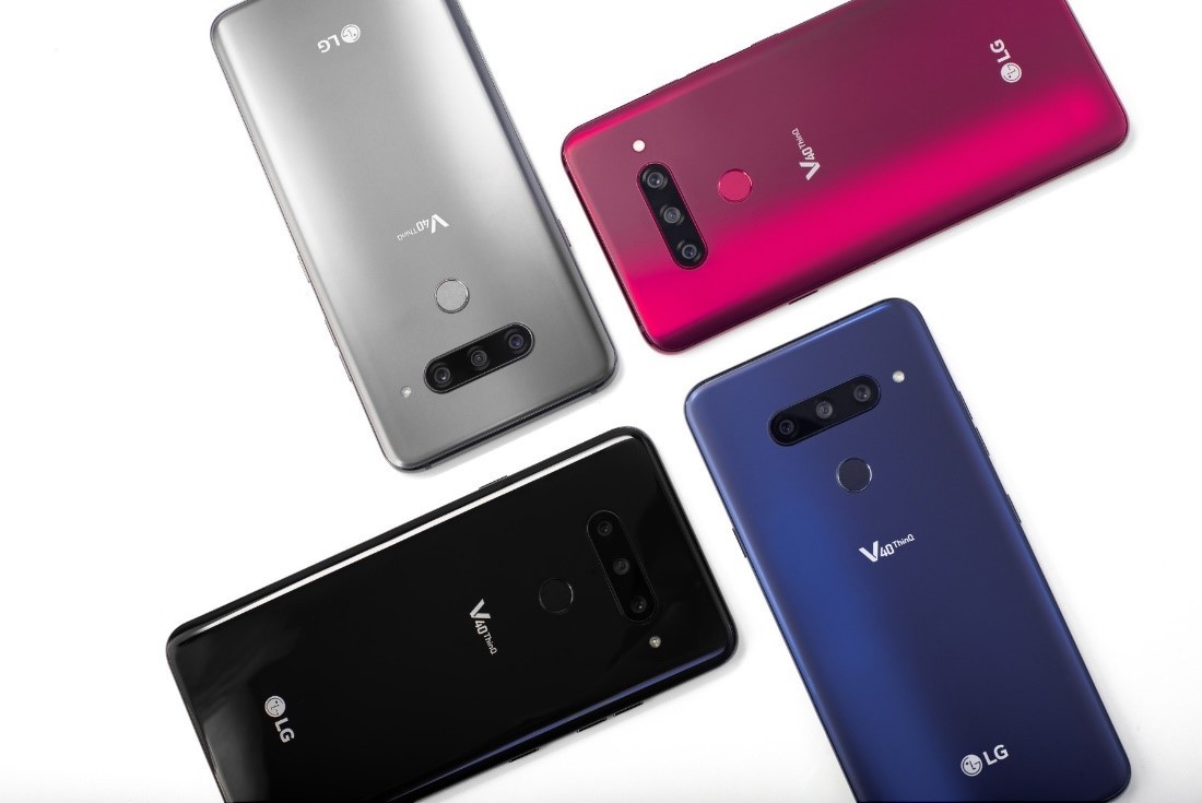 Four LG V40 ThinQ smartphones in New Aurora Black, New Platinum Grey, New Moroccan Blue and Carmine Red are placed in a brick pattern.