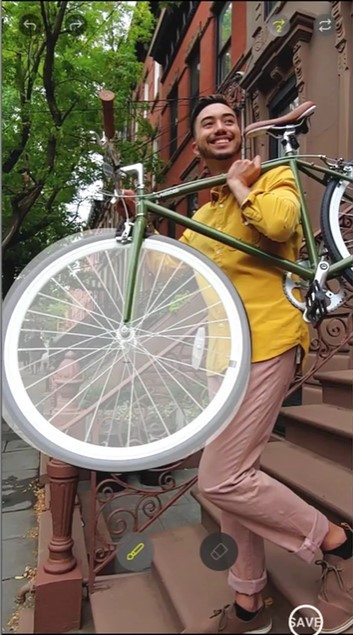 A still image of a six-second GIF image, a man walking down the porch stairs putting a bike on his shoulder