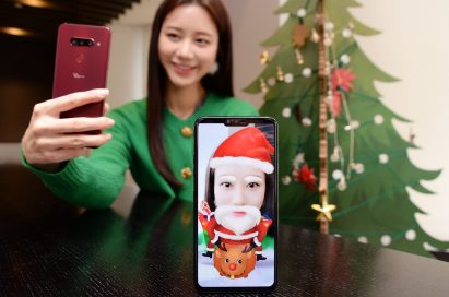 A woman turns her selfie into a Santa Claus lookalike by using the Augmented Reality (AR) sticker function of LG V40 ThinQ.