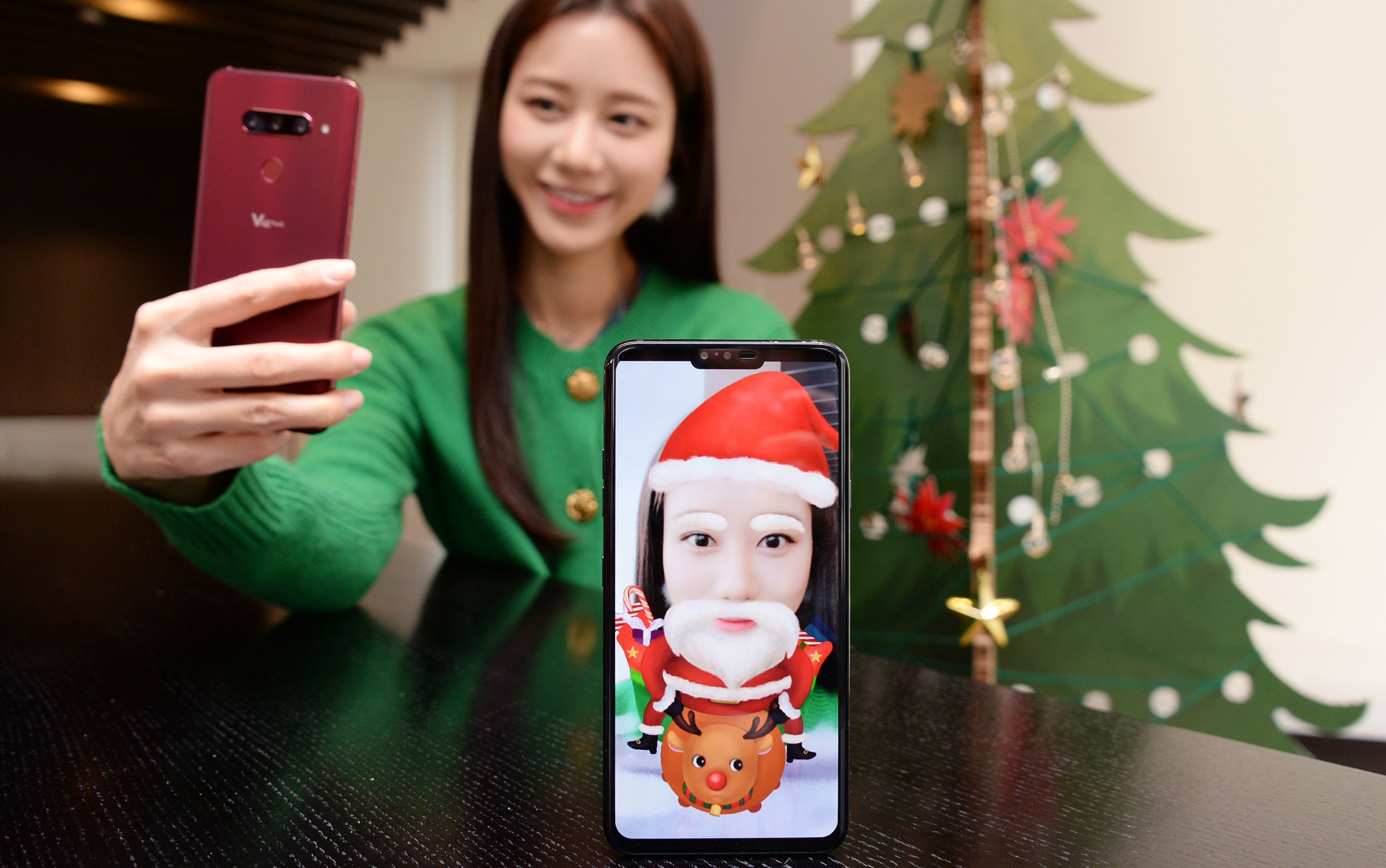 A woman turns her selfie into a Santa Claus lookalike by using the Augmented Reality (AR) sticker function of LG V40 ThinQ.
