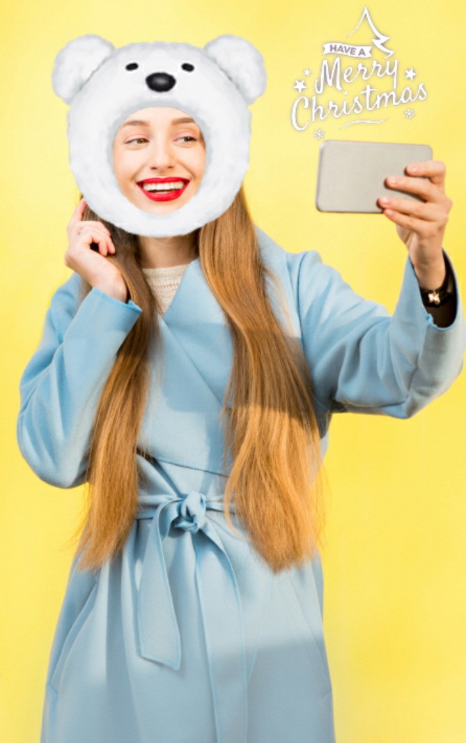 A woman takes a selfie as her face is decorated by a polar bear AR sticker.